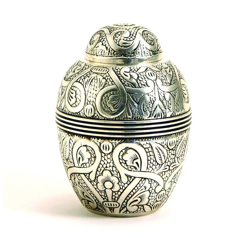 A nickel-plated brass pet urn with hand-engraved floral design.