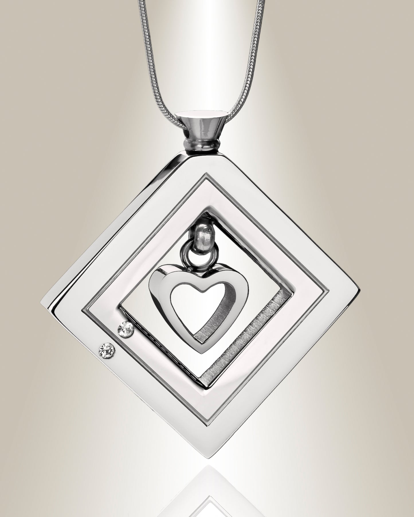 A silver heart-shaped cremation pendant with a grooved accent and clear stones, displayed on a chain.