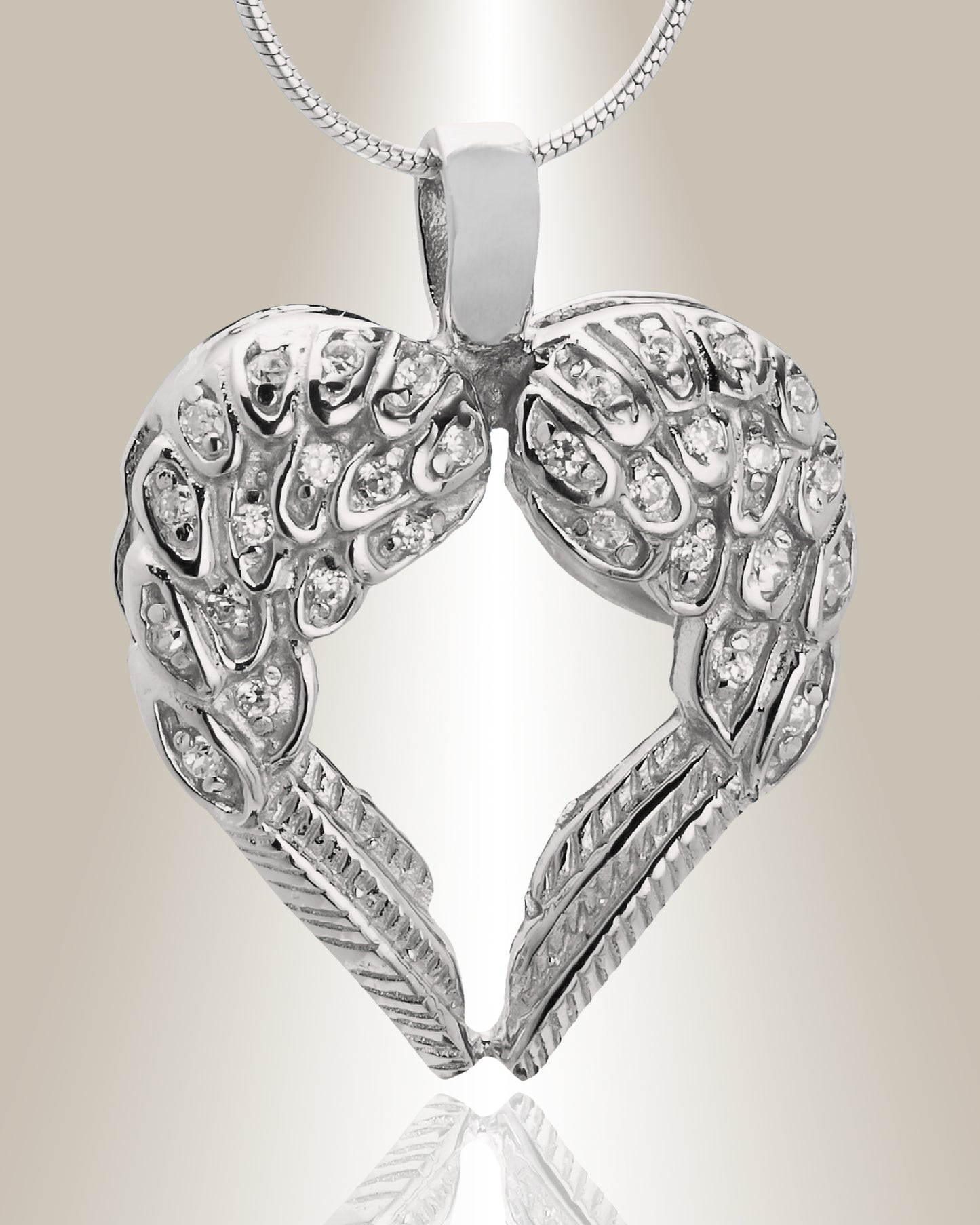 A silver cremation pendant in the shape of a heart with two wings, featuring gemstone accents at the top. The pendant is designed to hold ashes and comes with a chain.