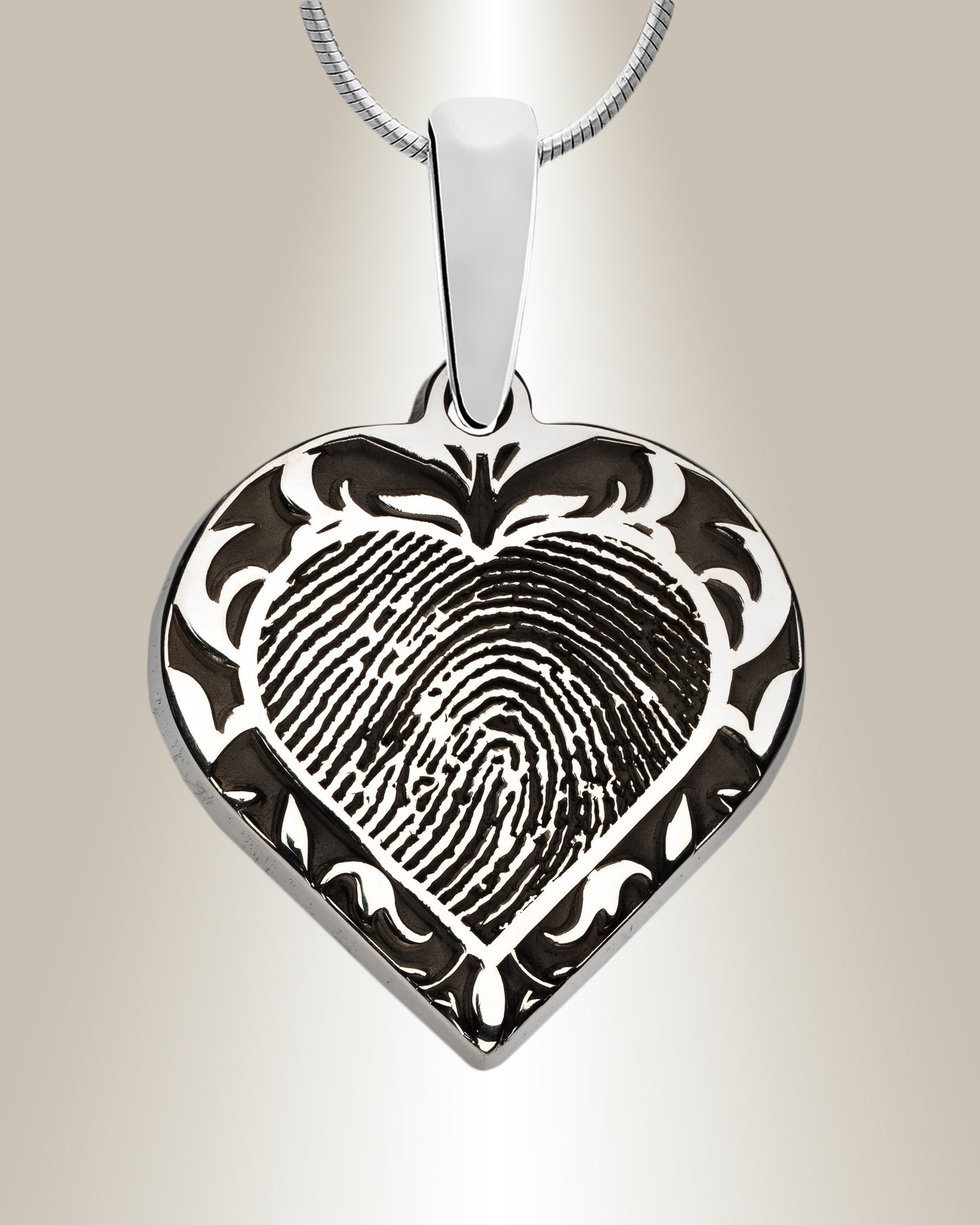 A sterling silver heart-shaped pendant with a filigree motif and a laser-engraved fingerprint in the center, accompanied by a 20-inch chain.