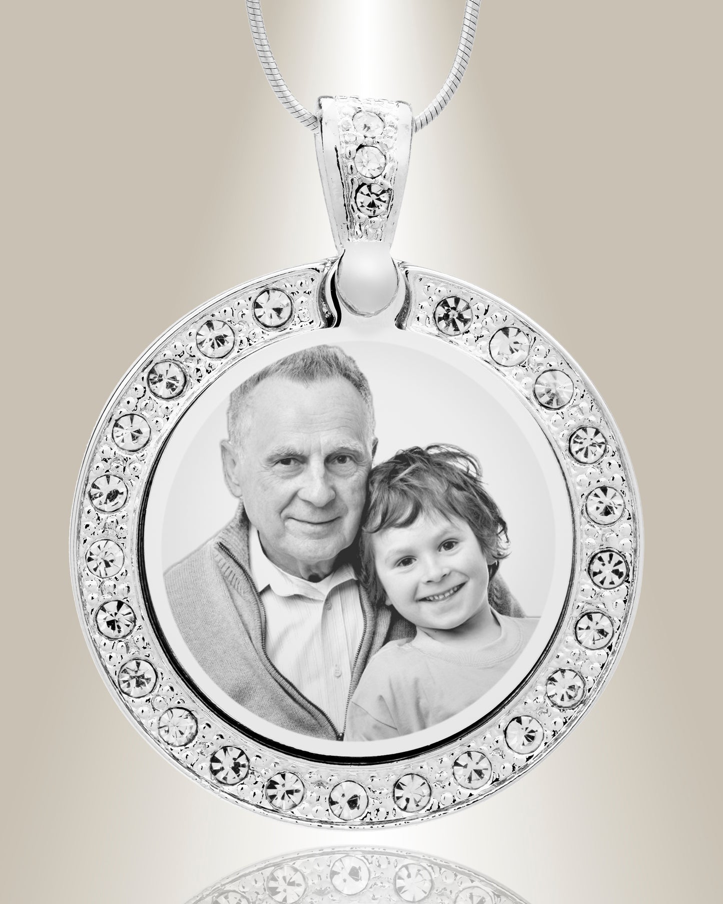 A stainless steel circle photo pendant with clear gemstones around the border, displaying an engraved photo of an older man and a young child.