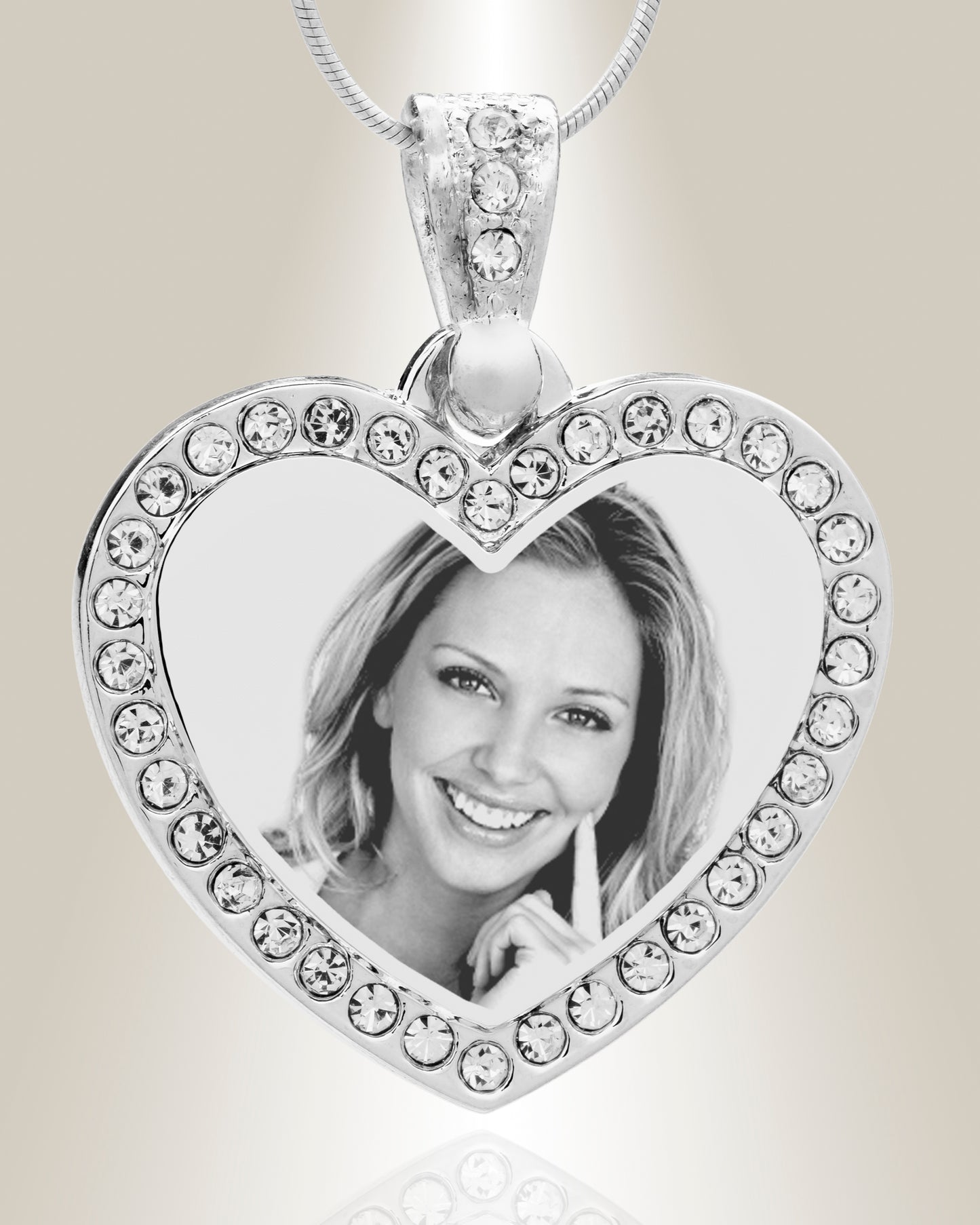 A heart-shaped stainless steel pendant with a photo engraved in the center, surrounded by clear gemstone accents, attached to a silver chain.