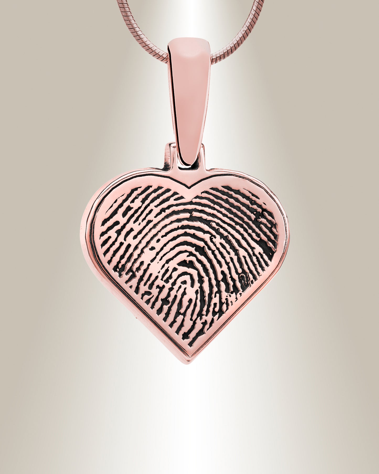A heart-shaped silver pendant with a fingerprint engraving on the front. The pendant appears to be attached to a chain.