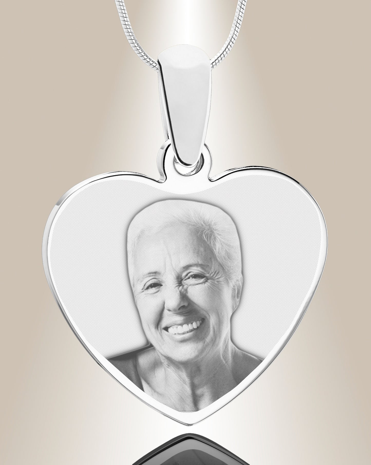 A stainless steel heart-shaped pendant with an engraved photo of a smiling person inside. The pendant is accompanied by a 20-inch chain.