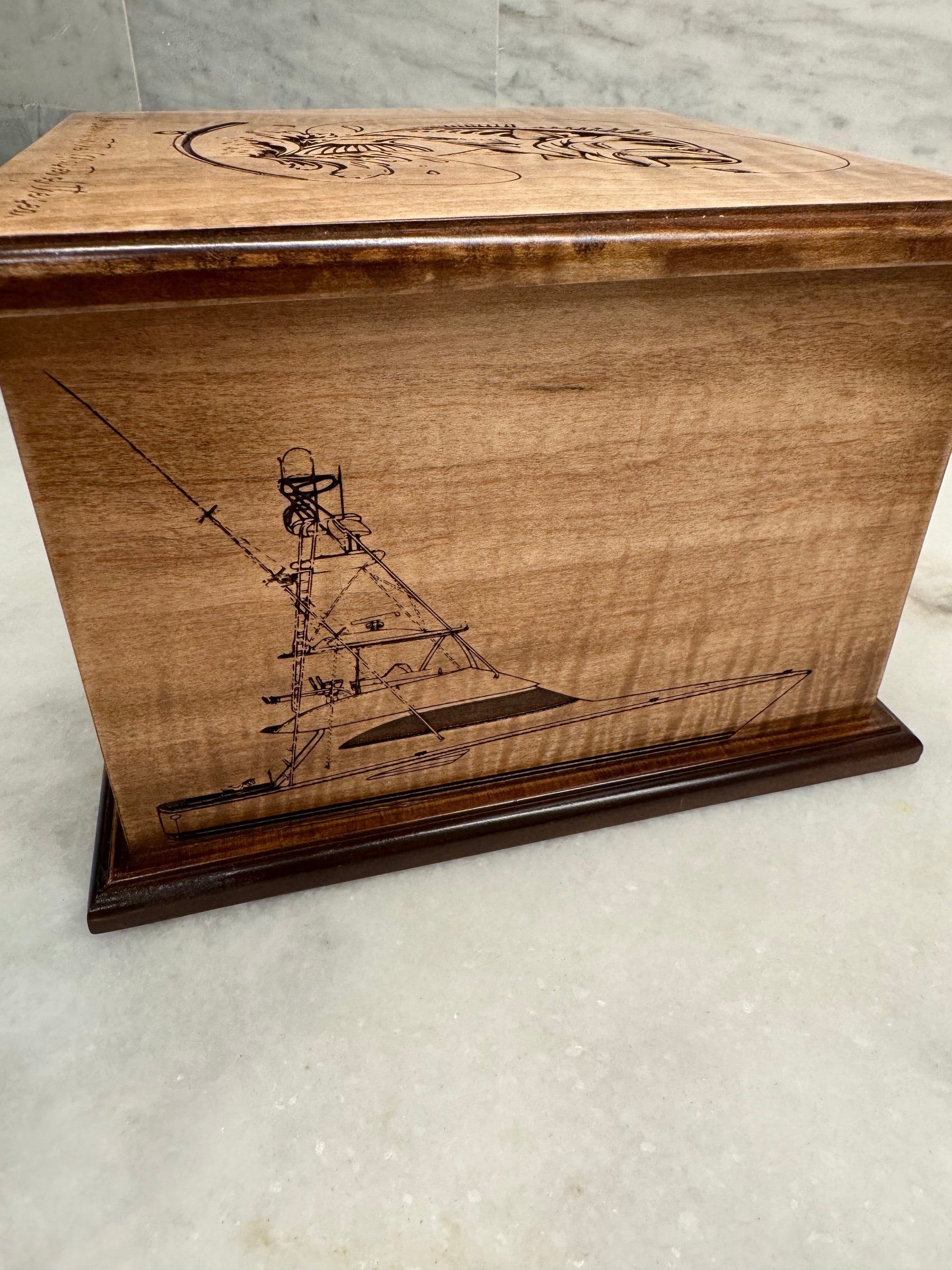 Custom wood urn with a detailed laser engraving of a sport fishing boat on the side.