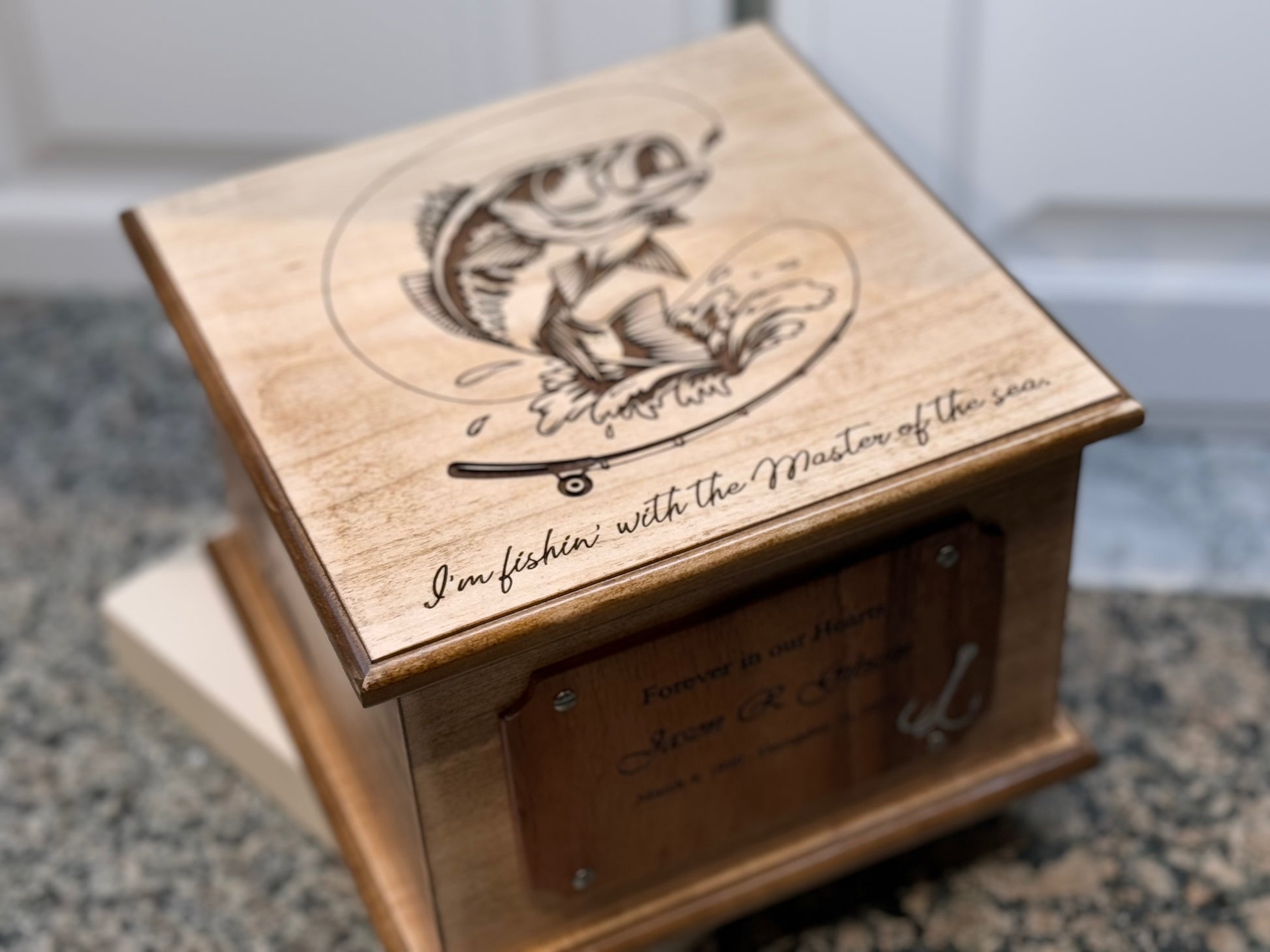 Custom wood urn with a dynamic laser engraving of a bass jumping from water on the lid.