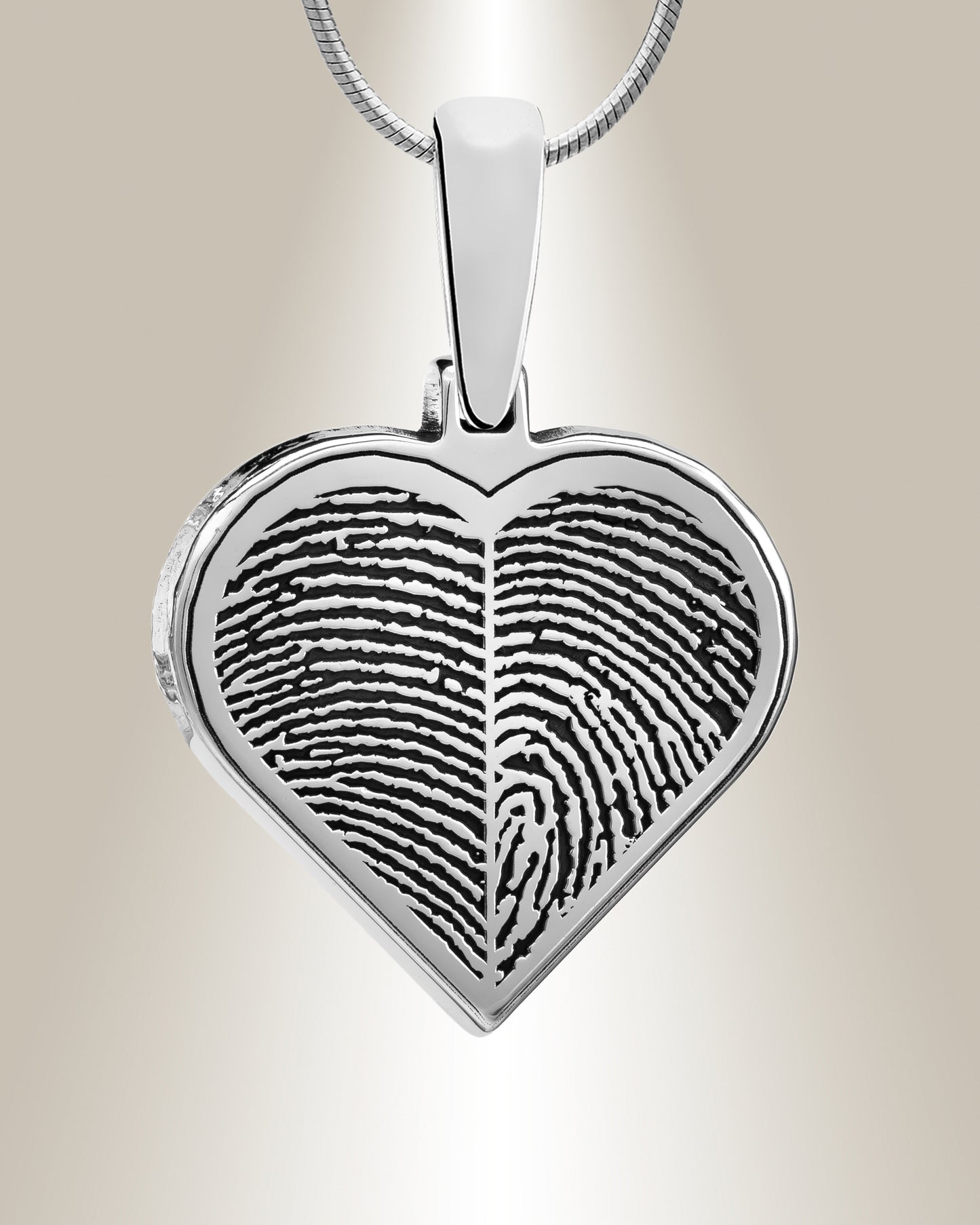 A silver heart-shaped pendant with a fingerprint engraved on the front, attached to a chain.