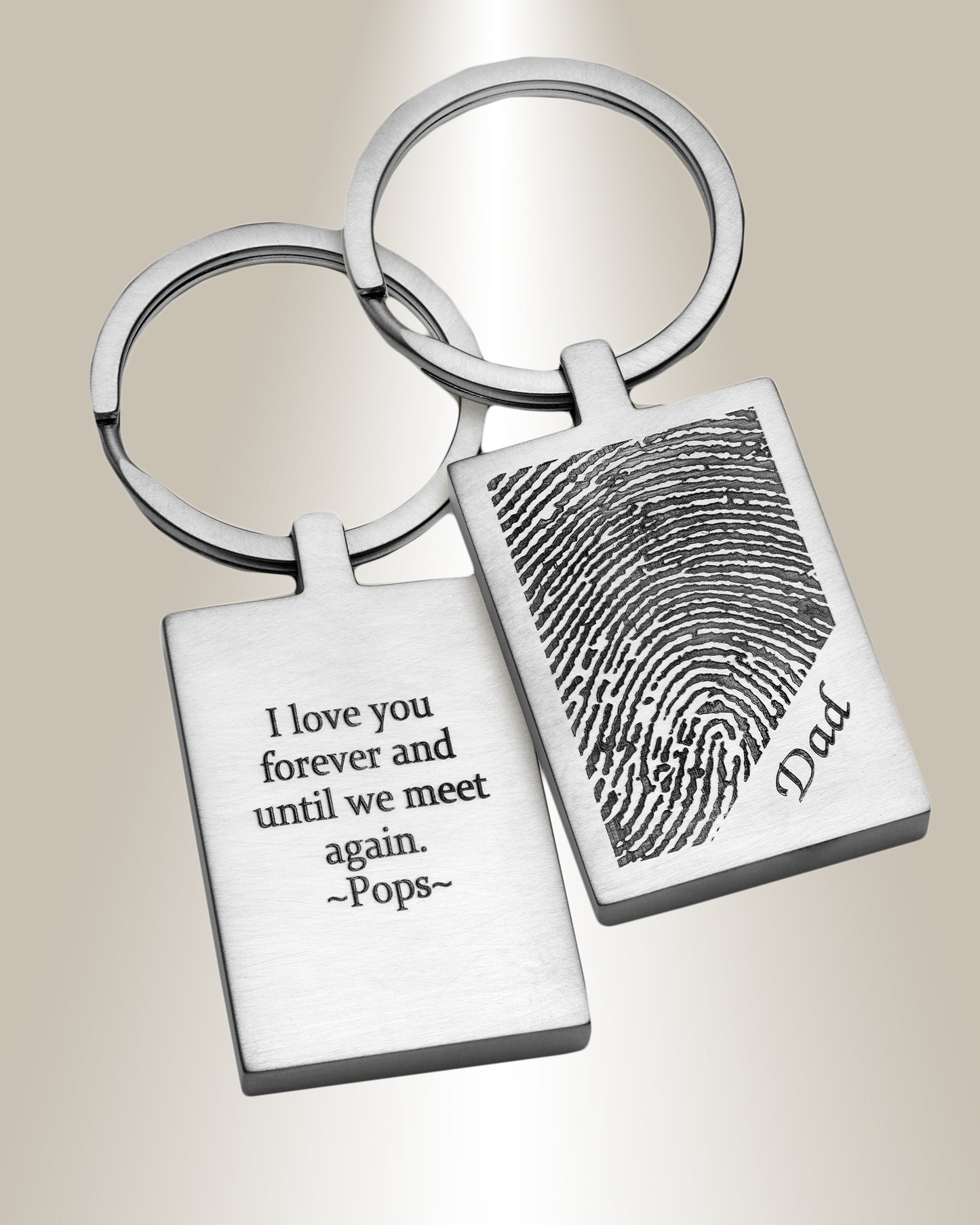 Two stainless steel keychains, one with a fingerprint image and the other with engraved text, attached to a keyring.