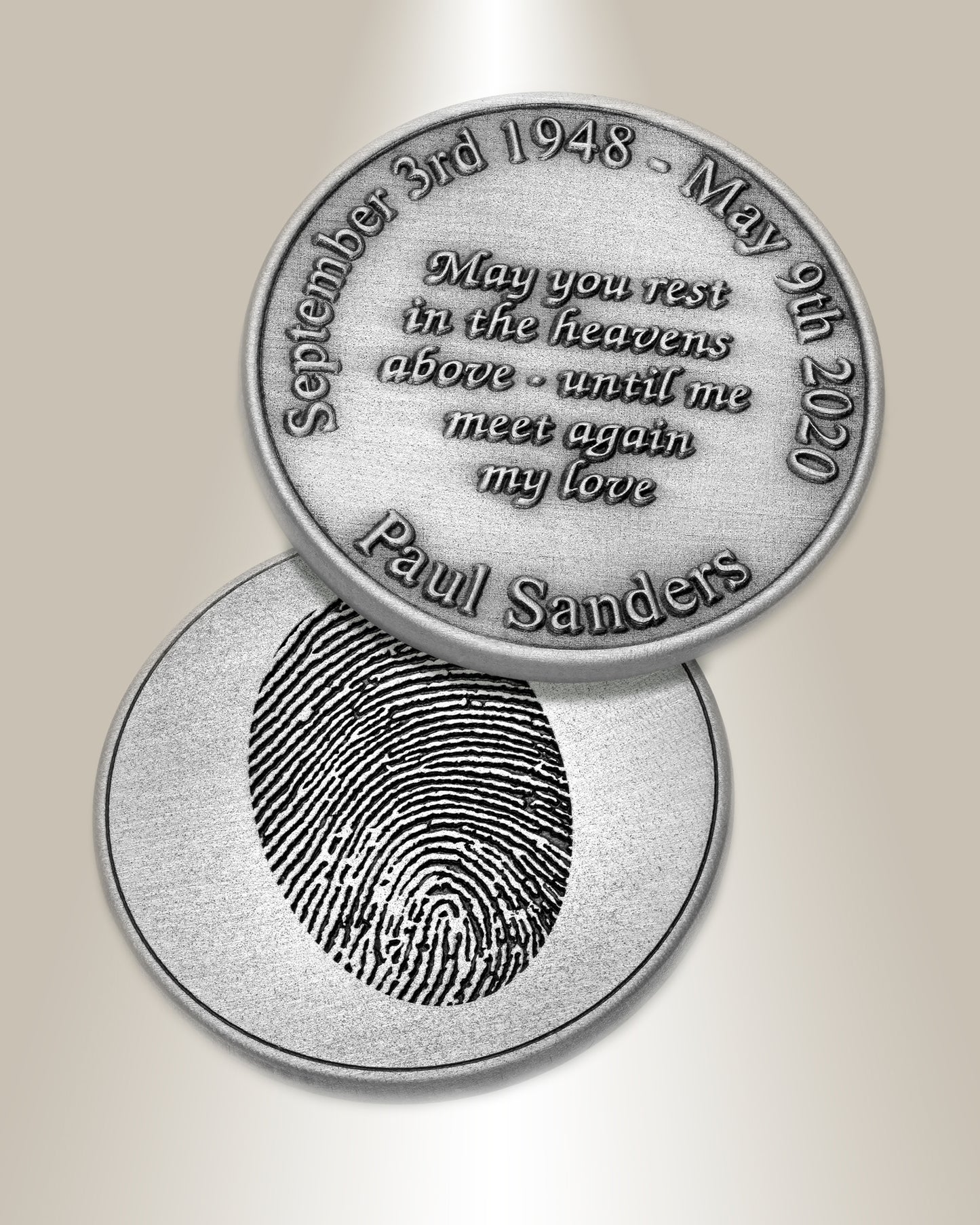 A silver coin with an engraved fingerprint on one side and text on the other, showing a proof finish.