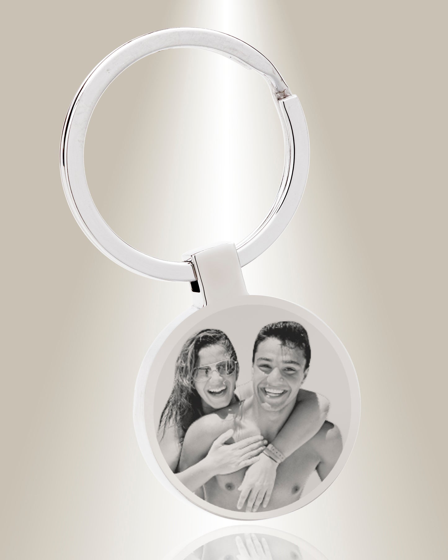 A round keychain with a photo engraved on it, featuring two individuals embracing.