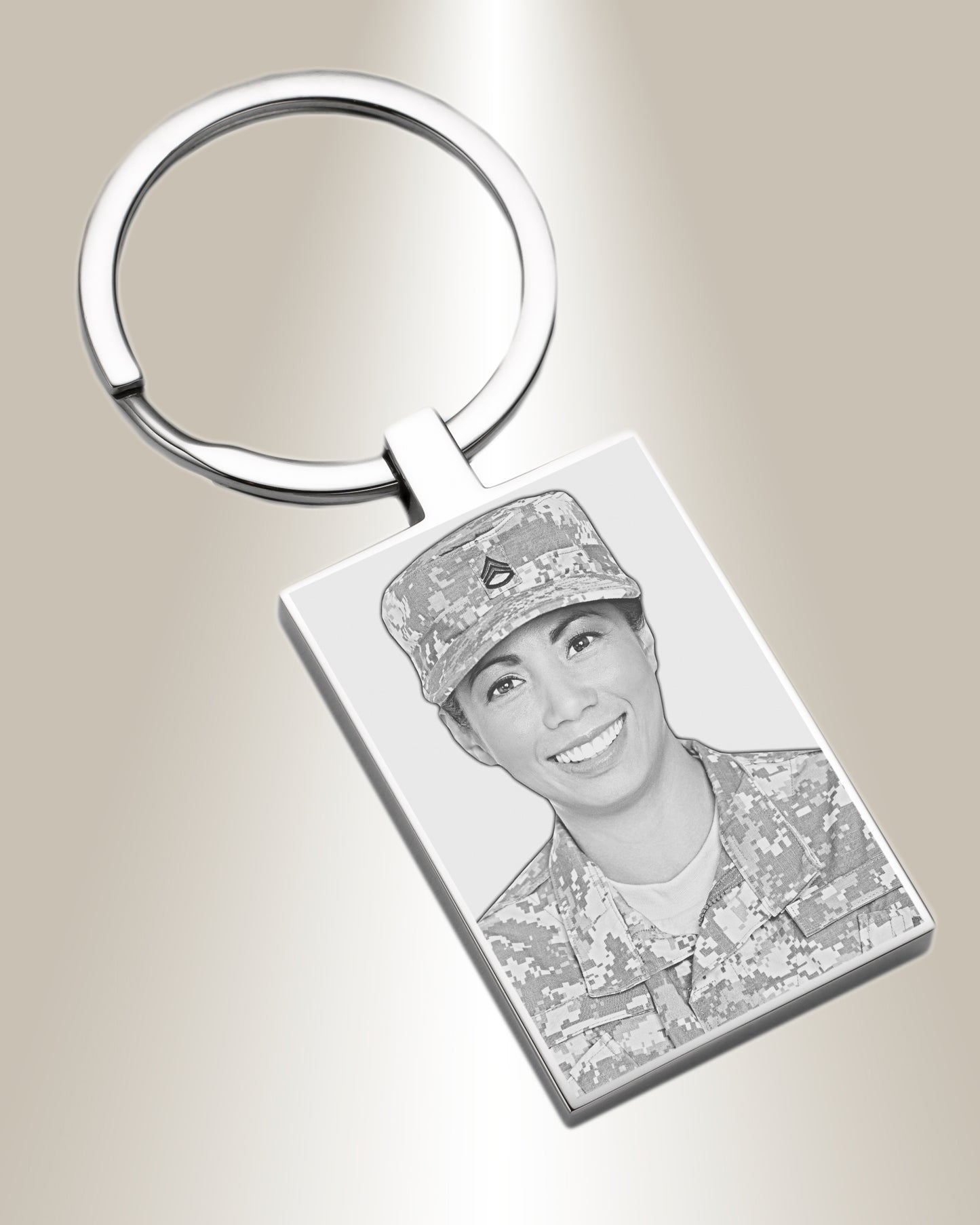 A silver-colored rectangle photo keychain with an engraved picture of a person wearing a military uniform.