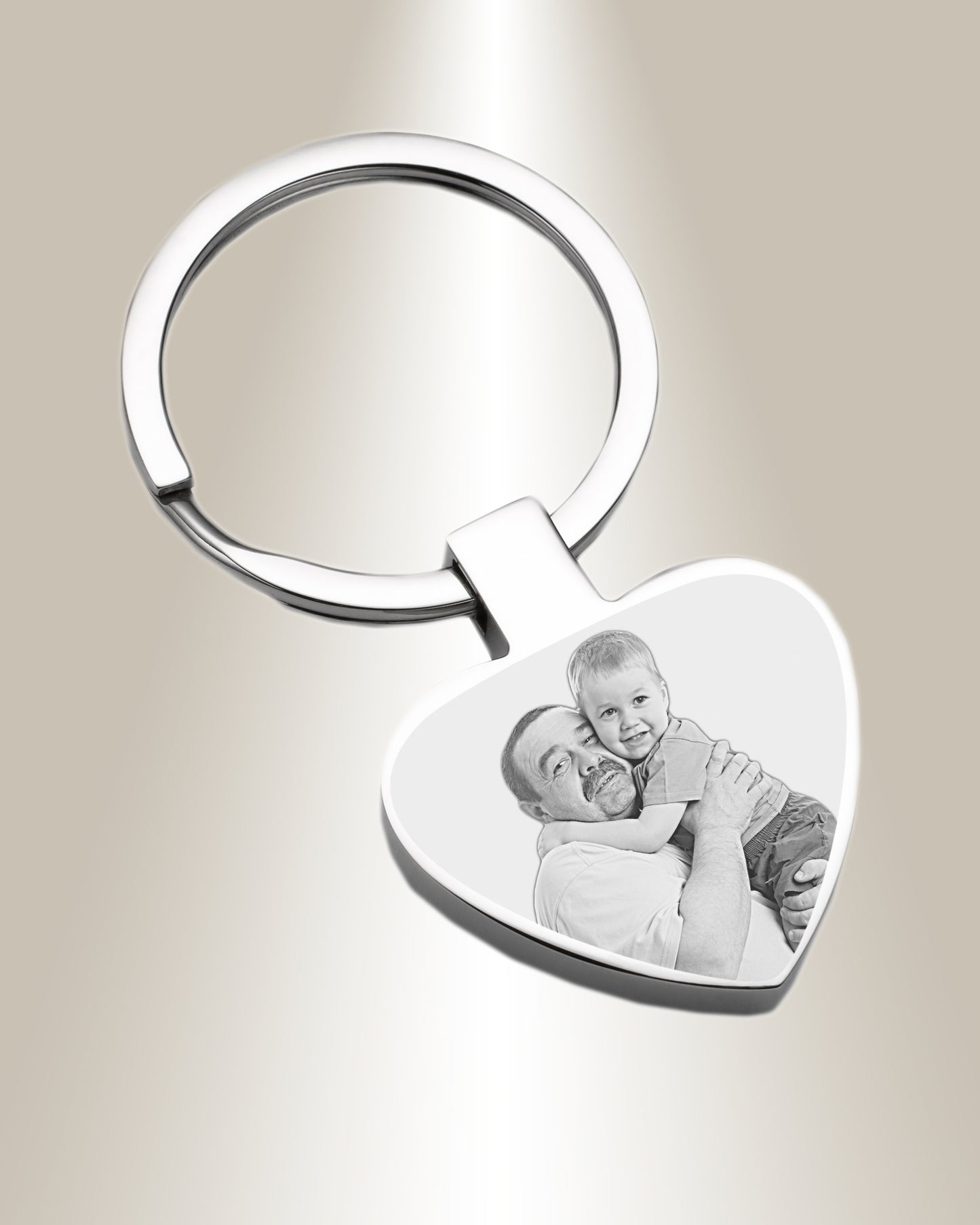 A heart-shaped silver keychain with a photo engraved on it.