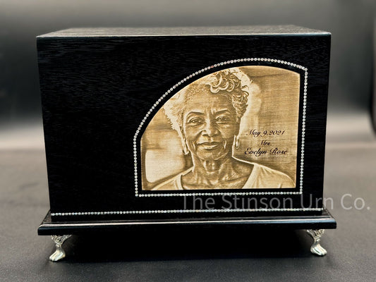 Custom made black urn with engraved portrait on a wood background. Made in Southern MD.