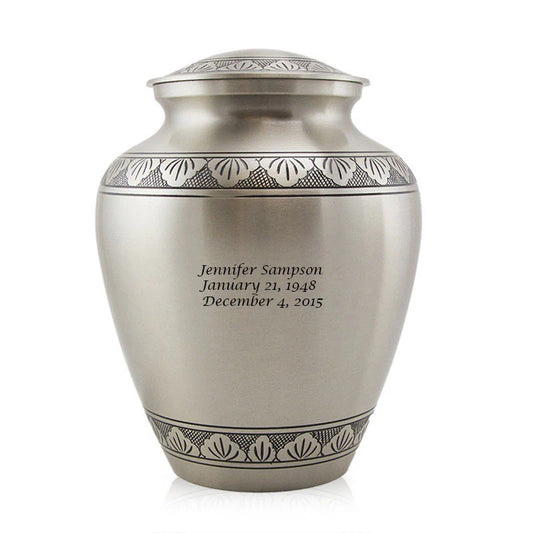 A traditionally shaped Grecian bronze cremation urn with a nickel plated finish, featuring hand etched floral band and a threaded lid. It has personalized engraving on the front.