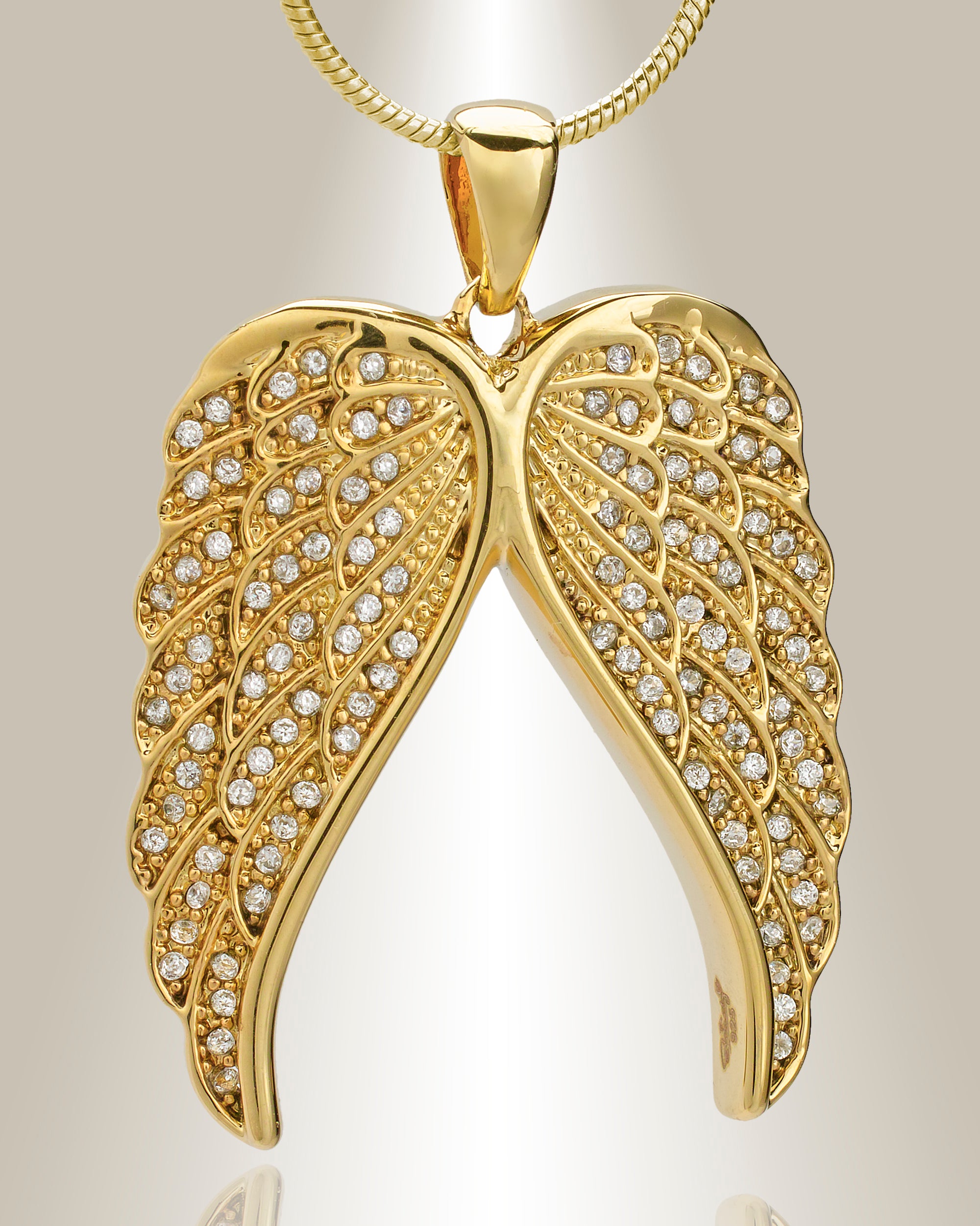 A gold-colored angel wings cremation pendant with clear gemstone accents, displayed with a 20-inch chain.