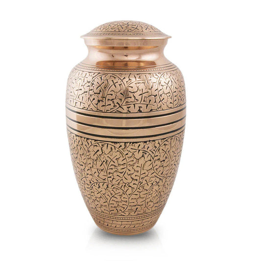 A large, intricately designed cremation urn made of bronze with copper plating, featuring an engraved oak leaf design.