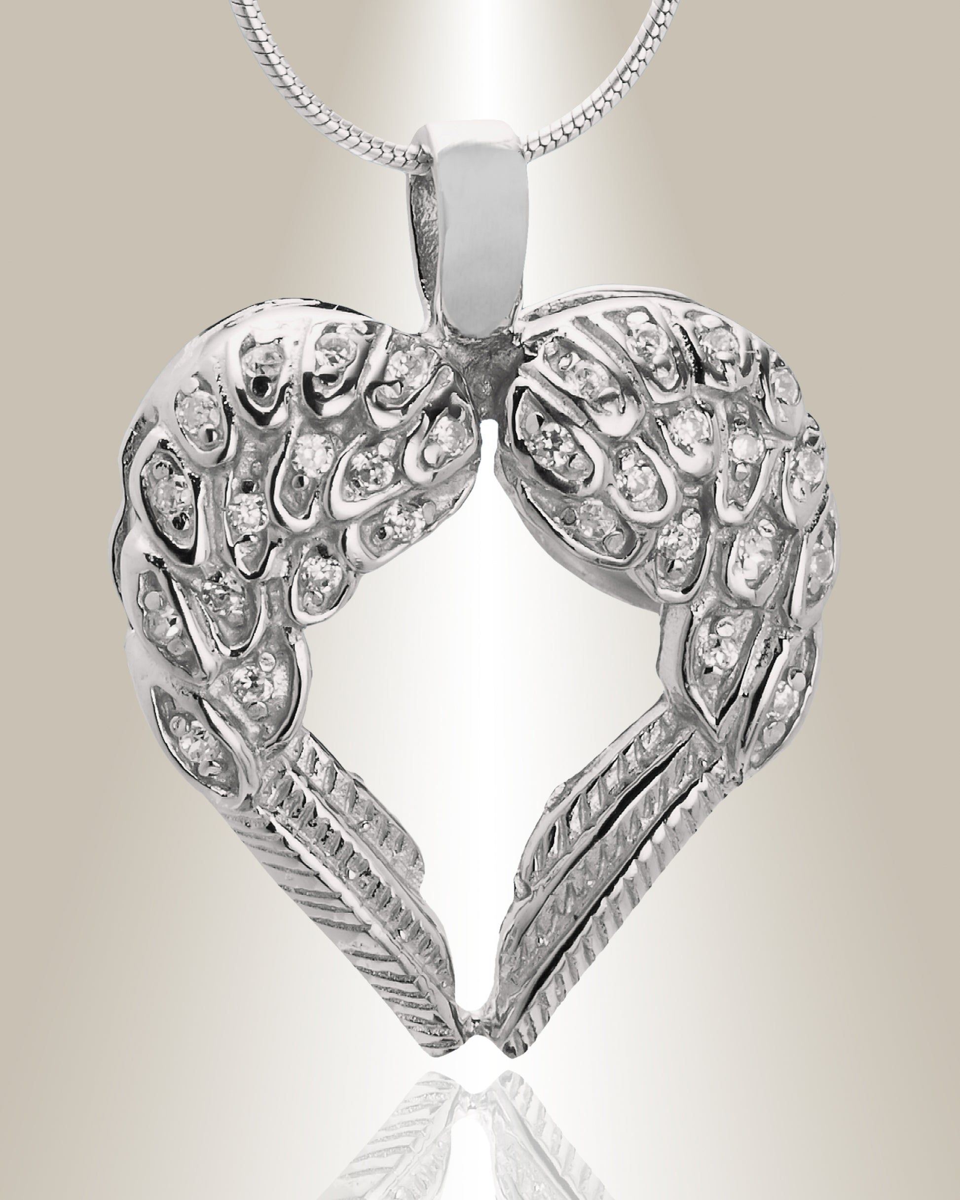 A silver cremation pendant in the shape of a heart with two wings, featuring gemstone accents at the top. The pendant is designed to hold ashes and comes with a chain.