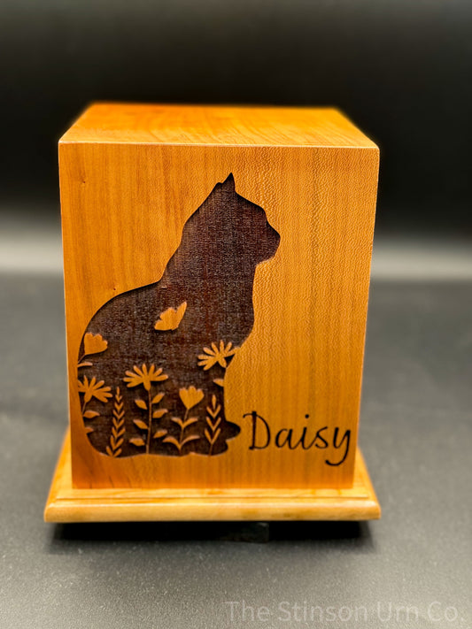 A wooden pet urn with a laser engraved silhouette of a cat named Daisy on the front.