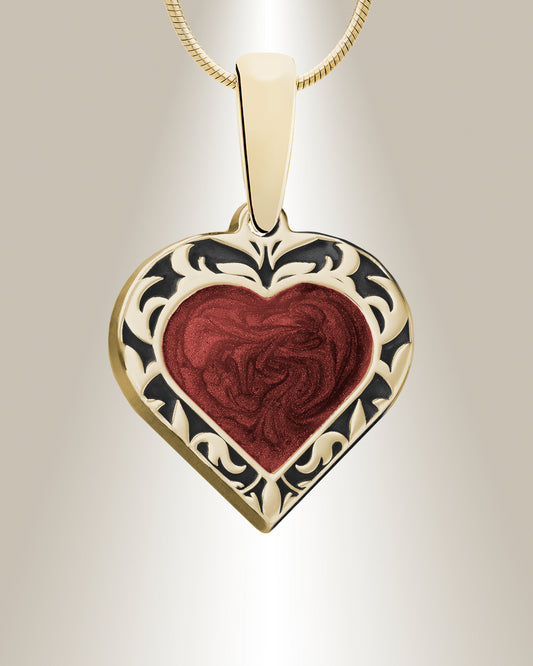 A heart-shaped pendant with a patterned edge and a crimson-colored center, resembling a blend of ashes and resin, displayed against a neutral background.
