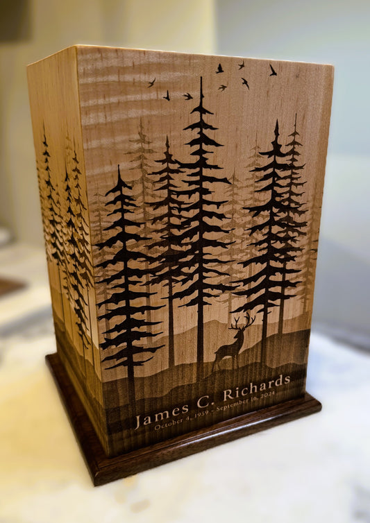 A wooden urn with a forest and deer design, featuring personalized text 'James G. Richards'.