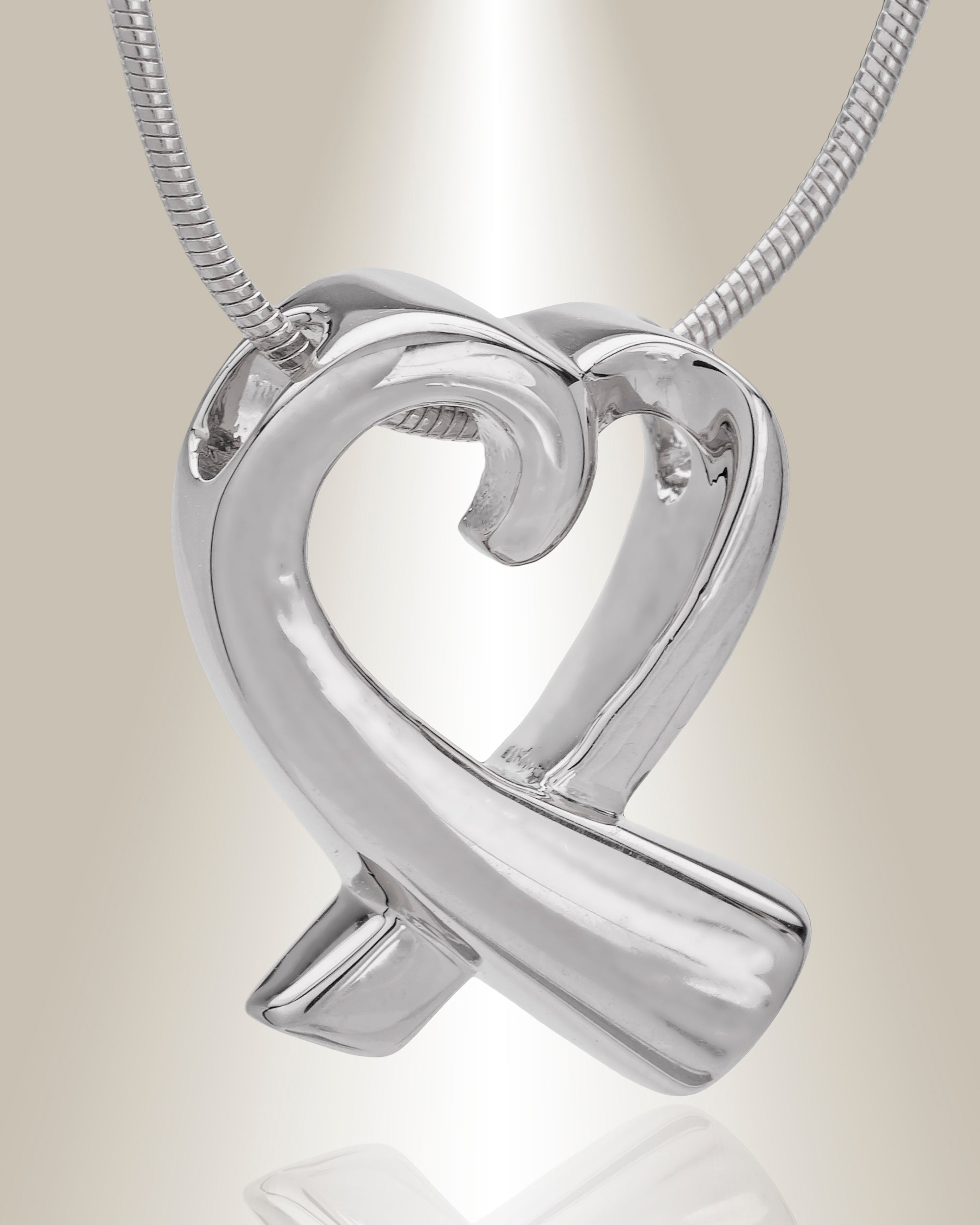 A silver heart-shaped cremation pendant with a butterfly motif on the top point, attached to a chain.