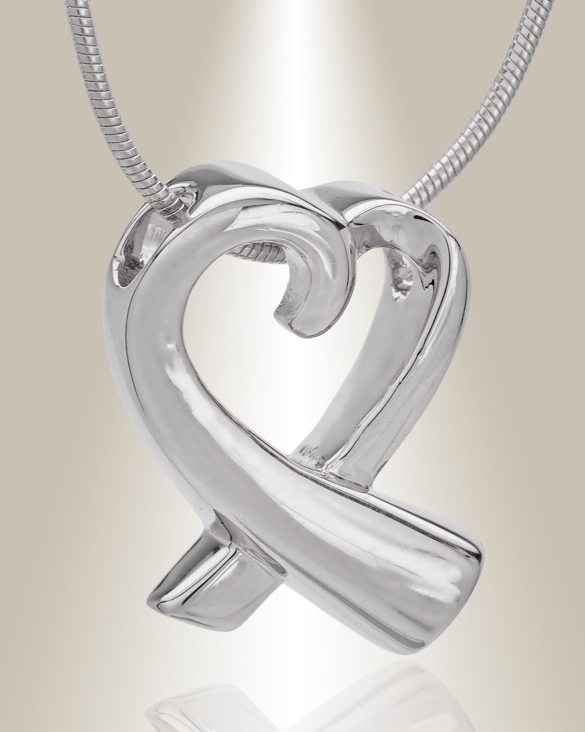 A silver heart-shaped cremation pendant with a butterfly motif on the top point, attached to a chain.