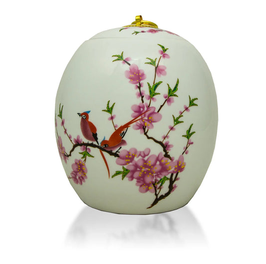 A white ceramic urn with hand-painted floral branch and love birds. The lid has copper plated ring handle.