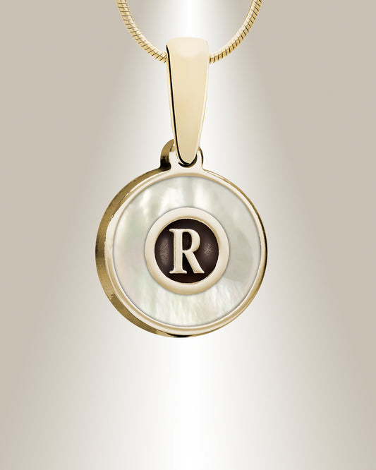 A sterling silver pendant with a personalized letter 'R' in the center, surrounded by a cream-colored resin, hanging from a gold-colored chain.