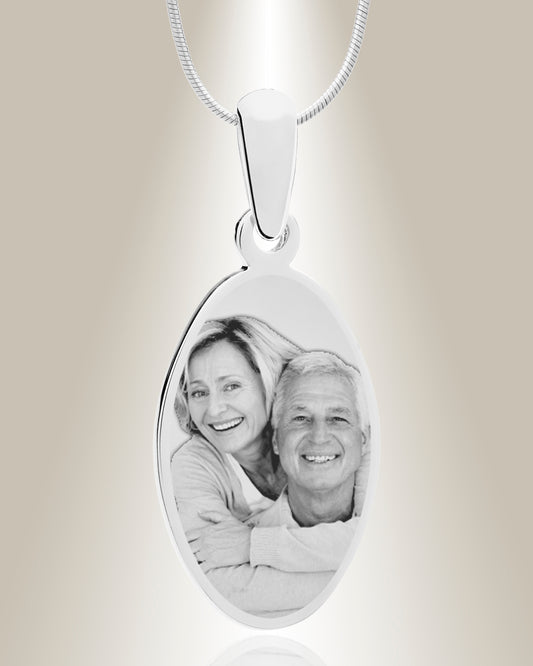 An oval-shaped stainless steel pendant with an engraved photo of a smiling couple, attached to a 20-inch chain.