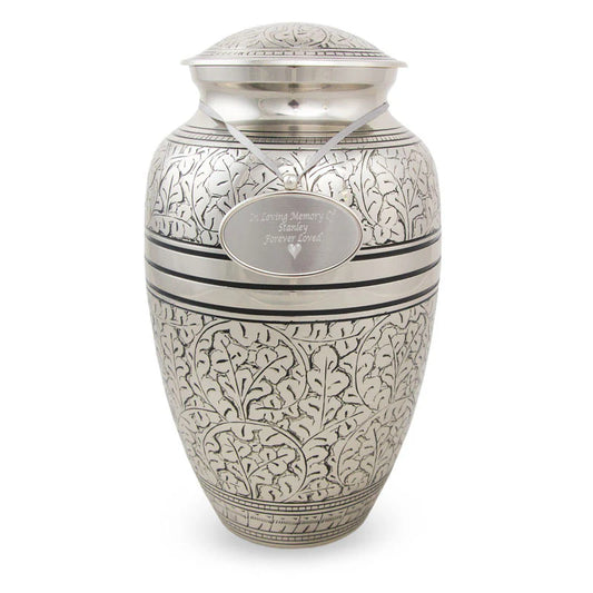 A large, nickel-plated bronze cremation urn with an oak leaf pattern, hand-engraved and placed against a white background.