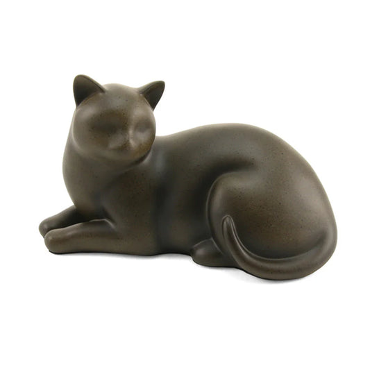 A handcrafted resin cat cremation urn in a warm sable color, resembling a reclining cat.