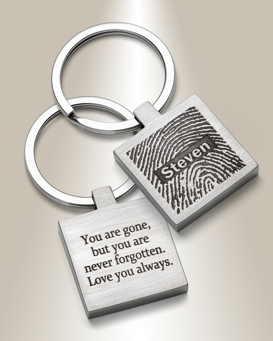 A stainless steel square fingerprint keychain with an engraved message on the back and a fingerprint image on the front.