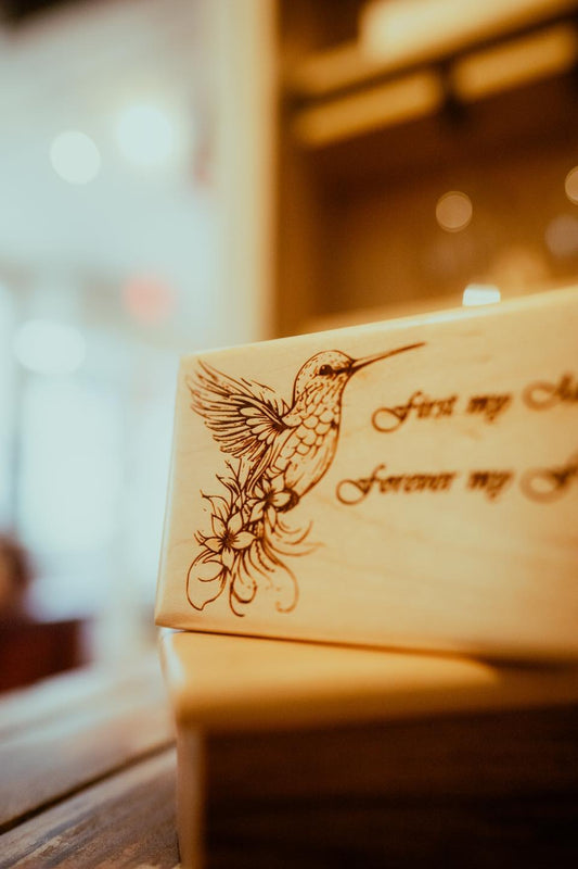 A wooden keepsake box with an engraved bird design and text that reads 'In my heart forever'.
