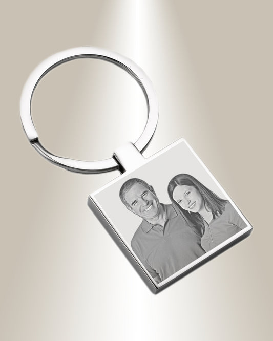 A silver square keychain with a photo engraved on it.
